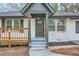 Close up on the front of the home, with a wood porch, gray roof, white brick, and an inviting front door at 2091 Parker Ranch Se Rd, Atlanta, GA 30316