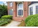 Detailed view of a stately brick home entrance with a dark front door and lush landscaping at 2613 Winterthur Main Nw, Kennesaw, GA 30144