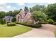 Traditional brick home with manicured bushes, green grass, and a large driveway at 2613 Winterthur Main Nw, Kennesaw, GA 30144