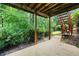 A covered patio area with stairs leading to an upper level and surrounded by lush greenery at 2613 Winterthur Main Nw, Kennesaw, GA 30144