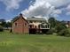 Expansive backyard view showcasing a deck, screened porch, brick home, and mature trees at 25 Darcee Ct, Lawrenceville, GA 30046