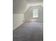 Cozy attic area featuring gray carpet, a large window, and a modern ceiling light at 3510 Hog Mountain Rd, Dacula, GA 30019