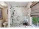 Luxurious glass shower with marble tiling, pebble floor, and a built-in bench by a window at 275 13Th Ne St # 201, Atlanta, GA 30309