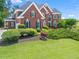Beautiful two-story red brick home featuring a manicured lawn, black shutters, and mature landscaping around the foundation at 1000 Gunter Ct, Alpharetta, GA 30022