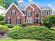 Charming red brick home featuring lush landscaping, black shutters, and a beautiful round turret on the right side at 1000 Gunter Ct, Alpharetta, GA 30022
