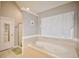 Bathroom with a soaking tub and tiled floors, with a window with blinds and curtains at 2540 Ridgehurst Dr, Buford, GA 30518