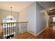Upstairs hallway features hardwood floors, iron railing, and natural light from a window at the landing at 2540 Ridgehurst Dr, Buford, GA 30518