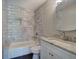 Updated bathroom featuring modern vanity, granite countertop, and a bathtub with tiled walls at 2646 Rockcliff Road Se, Atlanta, GA 30316
