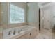 Bathroom showcasing a luxurious white soaking tub with tile surround and a window for natural light at 1101 Parkland Se Run, Smyrna, GA 30082