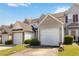 An exterior view of a townhome featuring a garage and well-maintained lawn with clear blue sky at 5351 Paramount View Way, Sugar Hill, GA 30518