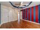 Bedroom with bold blue and red accents, double closets, and hardwood floors at 664 Johnson Rd, Oxford, GA 30054