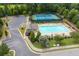 Aerial view of the community pool, tennis courts, and playground nestled among lush greenery at 7430 Ramsgate Ct, Cumming, GA 30040