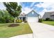 Charming blue home featuring a manicured lawn, colorful shrubs, and a classic two-car garage at 7430 Ramsgate Ct, Cumming, GA 30040