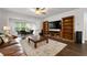 Bright living room featuring hardwood floors, built-in shelving, and a comfortable leather couch at 7430 Ramsgate Ct, Cumming, GA 30040