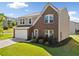 Inviting two-story home boasts a brick and siding exterior, attached garage, and a lush front lawn with appealing landscaping at 1560 Avalon Creek Rd, Sugar Hill, GA 30518