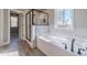 Bathroom with bathtub, marble wall tile, wood floors, and black fixtures and glass shower at 1500 Alcovy Station Rd, Covington, GA 30014