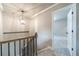 Carpeted hallway with neutral walls, decorative light fixture, and view into a bedroom at 1500 Alcovy Station Rd, Covington, GA 30014
