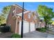 Side view of a well-maintained two-story brick home with a three-car garage and manicured landscaping at 401 Wellwood Way, Roswell, GA 30075