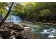 Picturesque scene of a waterfall cascading over rocks into a stream surrounded by lush trees at 401 Wellwood Way, Roswell, GA 30075