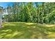 Lush backyard scene featuring a well-manicured lawn, a tranquil wooded backdrop, and a partial view of the home's exterior at 1114 Low Water Crossing Nw, Acworth, GA 30101