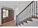 Welcoming home entry featuring a glass paneled wood front door and staircase with dark wood steps and white risers at 1114 Low Water Crossing Nw, Acworth, GA 30101
