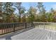 A wooden back deck overlooks a yard with lots of mature trees on a sunny day at 3198 Garden Hill Ln, Douglasville, GA 30135