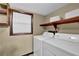 Functional laundry room featuring a washer, dryer, wooden shelving, and a bright window for added convenience at 102 Bascomb Drive Dr, Woodstock, GA 30189
