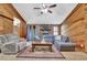 Inviting living room featuring wood paneled walls, a stone fireplace, and a ceiling fan at 102 Bascomb Drive Dr, Woodstock, GA 30189
