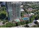 An aerial view shows the building with pool and tennis court amenities surrounded by greenery and cityscape at 2795 Peachtree Ne Rd # 703, Atlanta, GA 30305