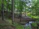 Lush wooded backyard featuring a stream and a stone path leading up to the house at 3365 Sweetwater Dr, Cumming, GA 30041