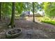 A backyard fire pit sits in front of a home surrounded by trees and a natural landscape at 3365 Sweetwater Dr, Cumming, GA 30041