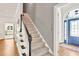 Carpeted stairway featuring wood railing, leading to the front door and kitchen area at 3365 Sweetwater Dr, Cumming, GA 30041