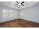Spacious main bedroom with a tray ceiling, large windows, and gorgeous wood floors at 264 Ascott Ln, Woodstock, GA 30189