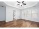 Bright main bedroom boasts wood floors, ceiling fan, tray ceiling, and windows at 264 Ascott Ln, Woodstock, GA 30189