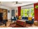 Cozy living room with hardwood floors, black leather sofa, red curtains, and plenty of natural light at 2468 Fallview Ter, Atlanta, GA 30344