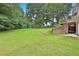 Large backyard with lush green grass, mature trees, and a patio area with a deck above at 245 Maple Shade Dr, Tyrone, GA 30290
