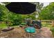 Stone patio with umbrella, play area, and storage under mature trees in the backyard at 4520 Dallas St, Acworth, GA 30101