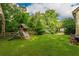 A sprawling backyard with a wooden playset, lush green grass, and mature trees, perfect for outdoor fun at 4520 Dallas St, Acworth, GA 30101