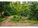 Serene backyard gravel area with a small patio, seating, and surrounded by lush greenery at 4520 Dallas St, Acworth, GA 30101