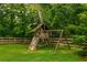 A charming wooden playset with a slide, climbing wall, and swingset sits in a private, fenced backyard at 4520 Dallas St, Acworth, GA 30101