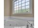 Close up of a large bathtub with chrome fixtures sitting under a large window with natural light at 102 Plantation Dr, Lagrange, GA 30277