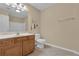 Bright bathroom featuring tiled floors, wooden vanity, a large mirror, and a white toilet and shower at 102 Plantation Dr, Lagrange, GA 30277