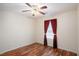 Bedroom featuring hardwood floors, ceiling fan, and window with red and brown curtains at 40 Browning Dr, Covington, GA 30016