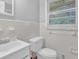 Bathroom with white tile, featuring a toilet and sink with window light at 1724 Rhonda Ln, Stone Mountain, GA 30087