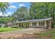 Charming ranch-style home with a brick facade, covered porch, mature trees, and a spacious driveway at 1724 Rhonda Ln, Stone Mountain, GA 30087