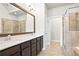 Bright bathroom boasts a large mirror over a dual sink vanity and a tiled shower with a glass door at 3657 Atherton Park Ct, Suwanee, GA 30024