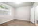 Bedroom with wood-look floors, neutral walls, large window, white trim, and adjacent bathroom at 3657 Atherton Park Ct, Suwanee, GA 30024