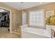 Well-lit bathroom featuring a soaking tub, glass-enclosed shower, and decorative window at 610 Syemore Pass, Canton, GA 30115