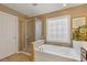 Bathroom with soaking tub, glass-enclosed shower, and framed decorative window at 610 Syemore Pass, Canton, GA 30115