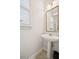 Powder room with pedestal sink, gold-trimmed mirror, and window with blinds at 130 White Sands Ct, Suwanee, GA 30024